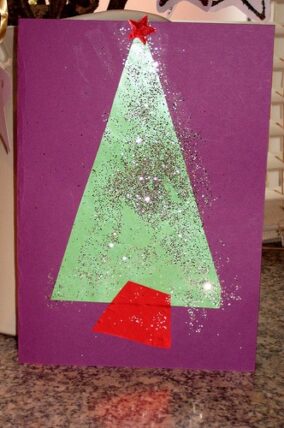 Handmade Christmas card with a glittery green paper tree on purple