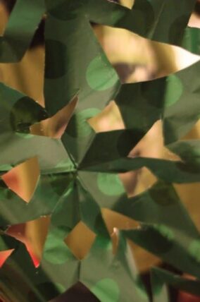 Paper snowflake folded from green and gold wrapping paper