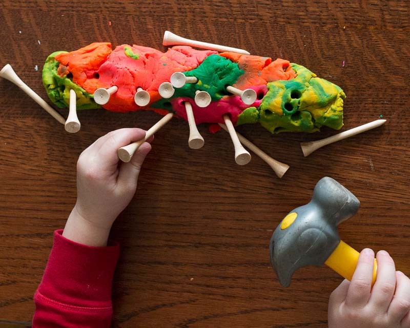 Hammering tees into play dough for toddlers to work on hand and eye coordination