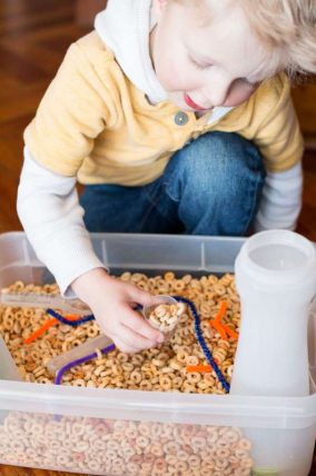 A simple cereal sensory bin for toddlers with threading activity