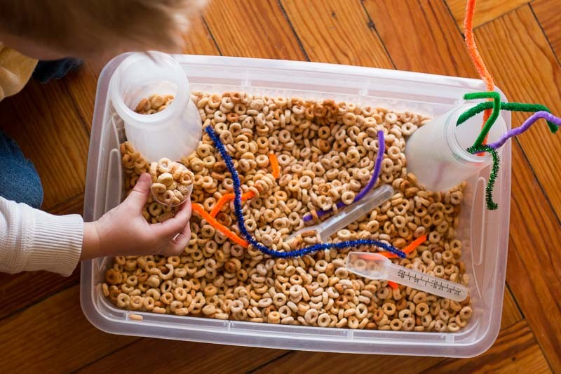A simple cereal sensory bin for toddlers with threading activity 