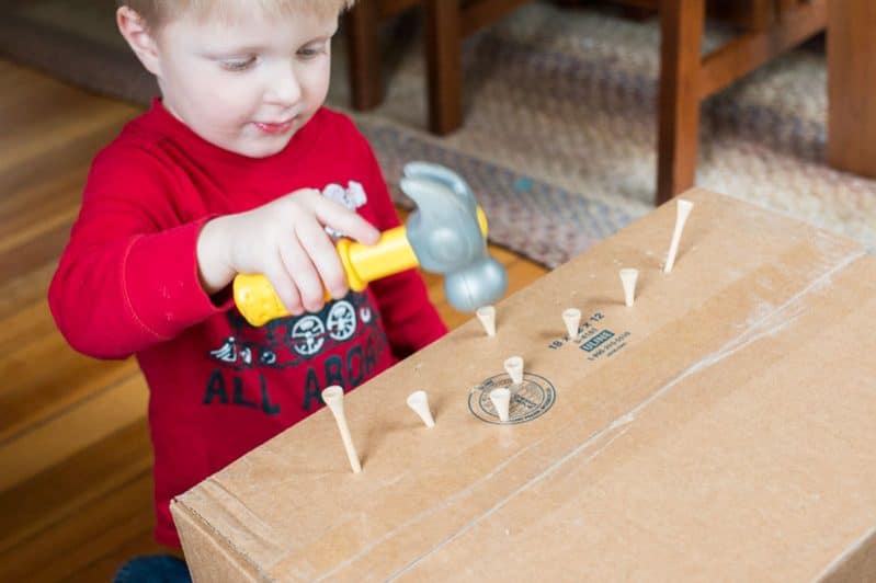 Work on fine motor skills with this super simple no prep hammering activity for toddlers using a cardboard box, golf tees, and toy hammer.