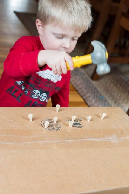 Upcycle a cardboard box with this simple fine motor hammering activity using golf tees. Perfect low prep activity for toddlers and preschoolers to do at home.