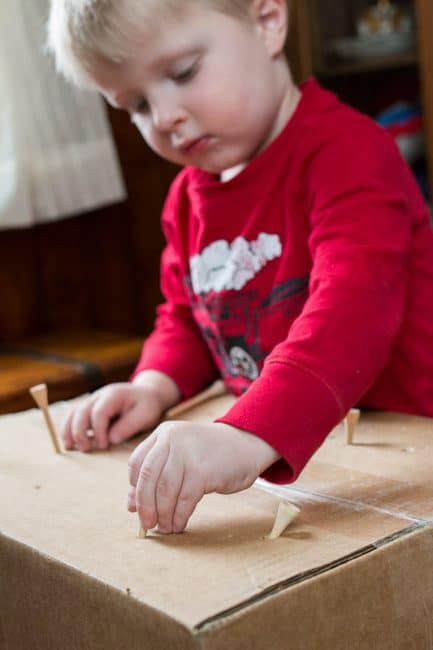 Poking tees into a cardboard box - great idea for fine motor skills for toddlers