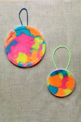 Child's hands pressing colored beads into play dough