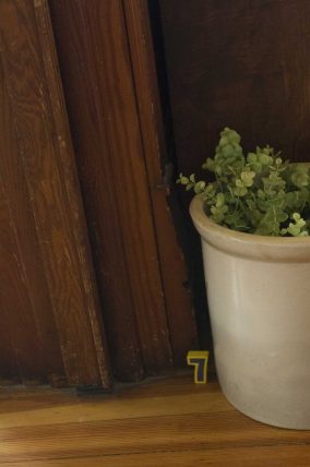 A number seven card tucked against a potted plant by a doorway