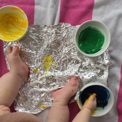 This baby foil painting art activity is messy, but so much fun! Learn how to make instant edible finger paint to make painting on foil safe for you baby.