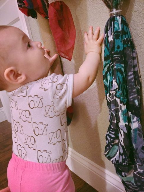 Try this simple baby scarf pull activity to get your baby moving! Encourage gross motor skills with this low-prep baby play idea.