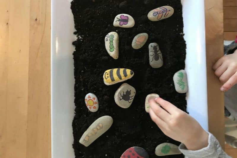 Tell a story with story stones using a sensory tray of dirt as a backdrop.