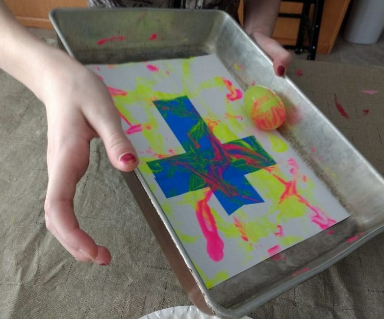 Roll and paint a tape resist cross using plastic Easter eggs!