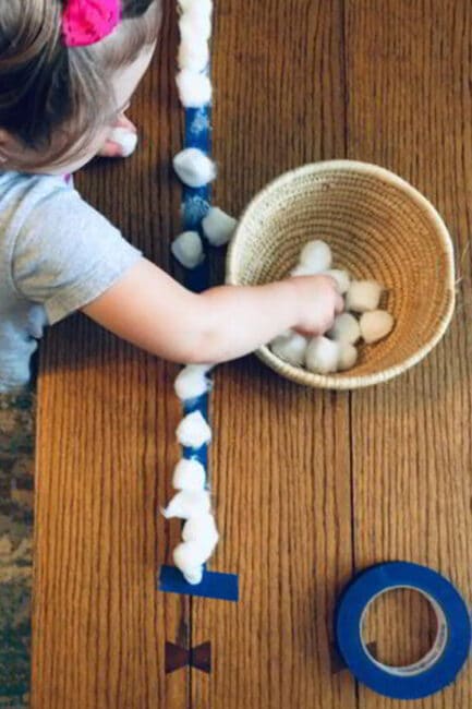 Work on fine motor skills with a quick cotton ball lineup for your toddler.