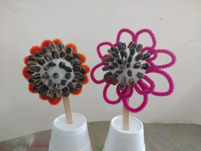 super simple pipe cleaner flowers for preschooler to make with sunflower seed centers -- a fun spring flower craft!