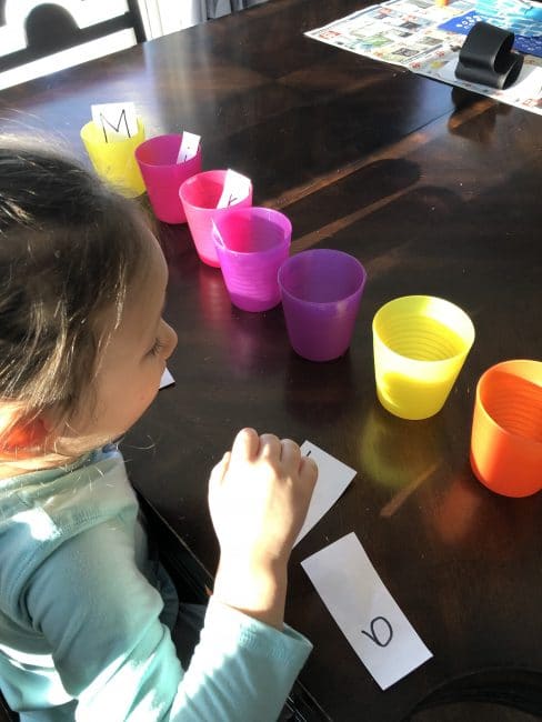 Putting the letters of your child's name into cups.
