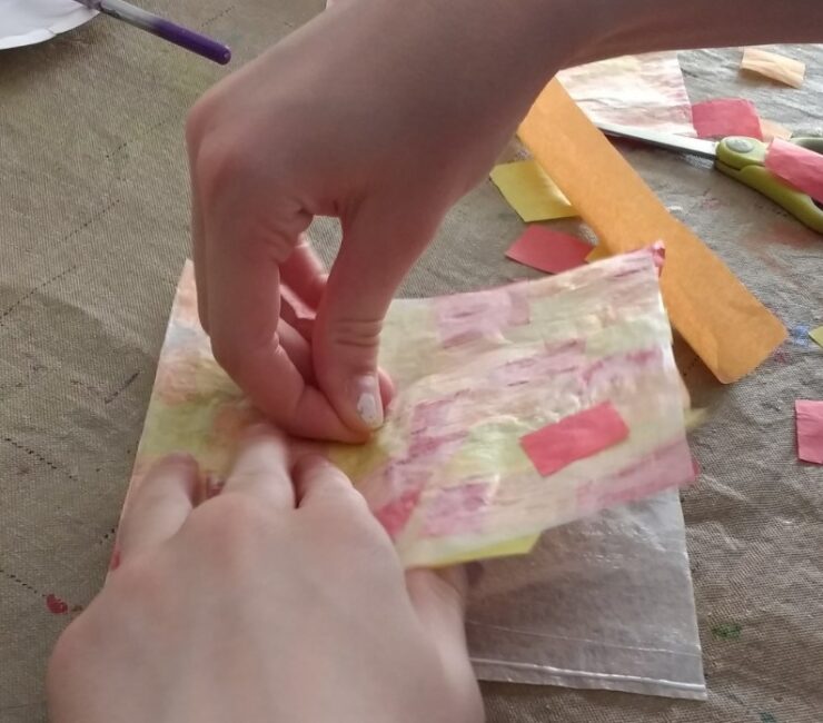 Gluing tissue paper between wax paper for easy fall leaf suncatcher craft for kids.