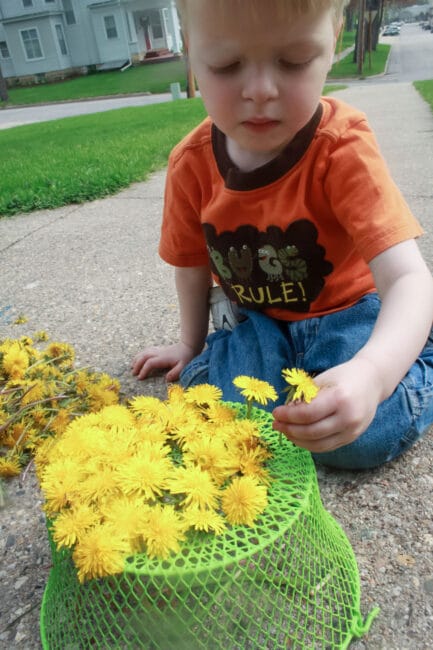 Outdoor play: Threading dandelions into a basket to make a hat.