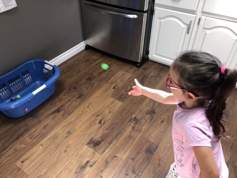 Trying to get the bouncy balls in the laundry basket!