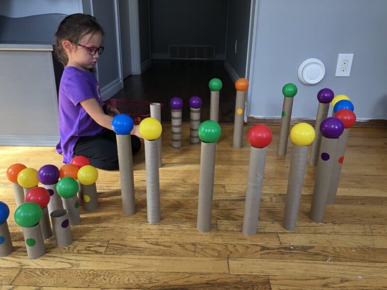 Making a fort with ball pit balls and paper rolls for fine motor fun.