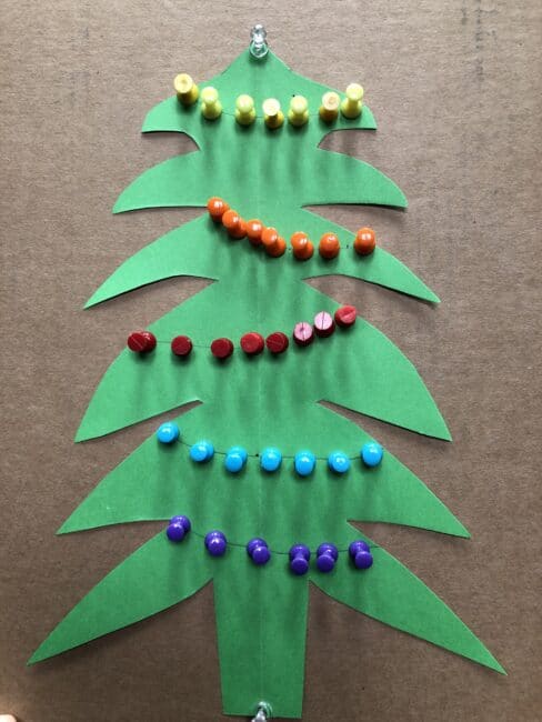 A perfect Christmas fine motor activity for kids to create a tree with push pins, paper and a cardboard box! Sort colors or make patterns.