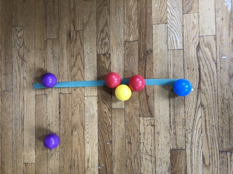 Sticky line ball rolling activity for kids to do at home with ball pit balls.