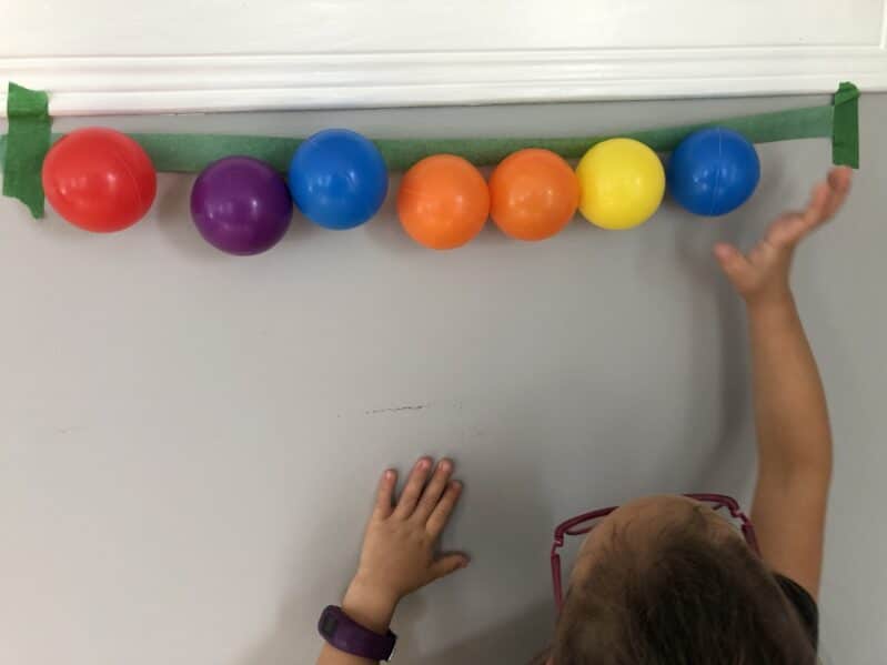 Reach up and stick balls to a line of painters tape for gross motor fun at home.