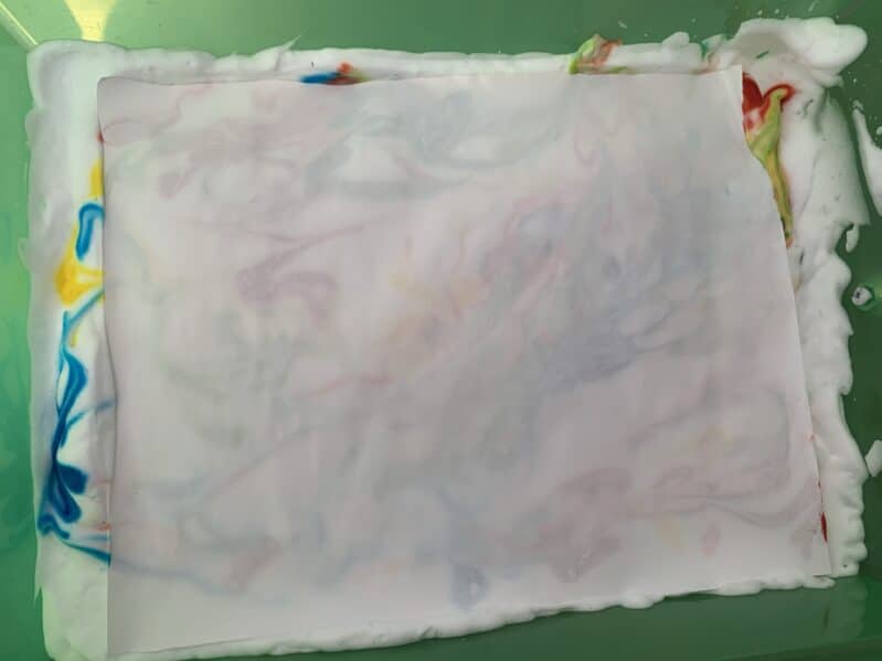Making marbled wrapping paper art with shaving cream and food coloring.