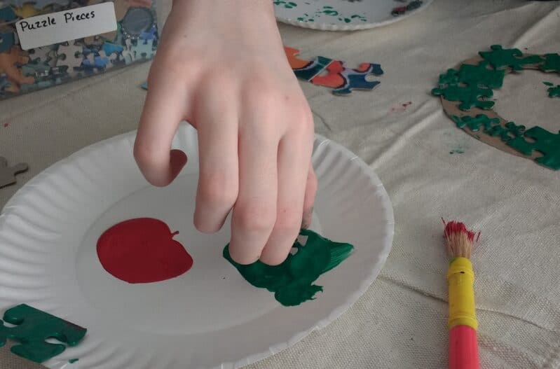 Dipping puzzle pieces in paint for Christmas wreath