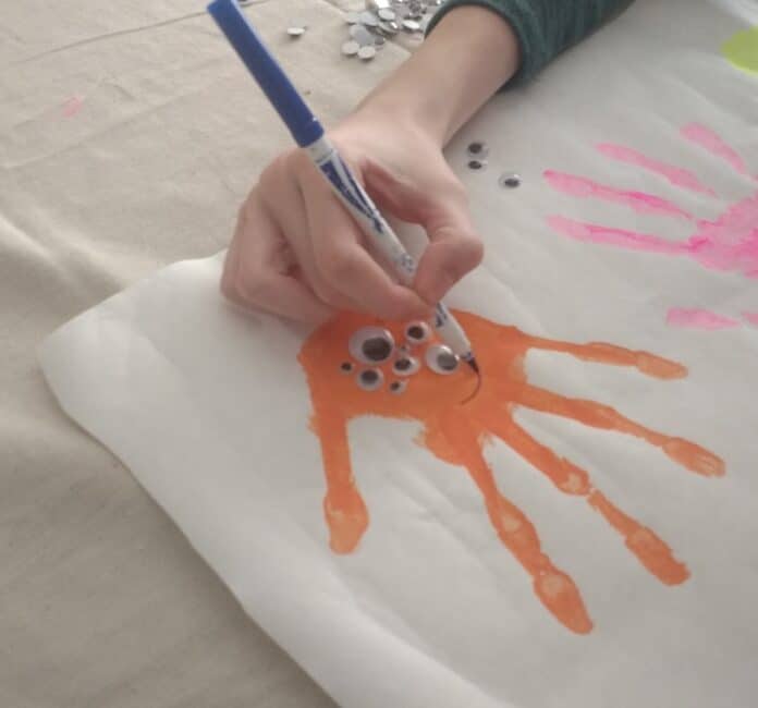 Drawing faces on the googly eye handprint monsters