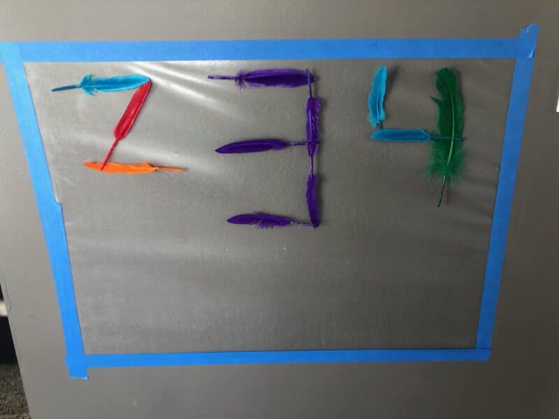 Numbers activity or just sensory play with feather and contact paper on the wall.