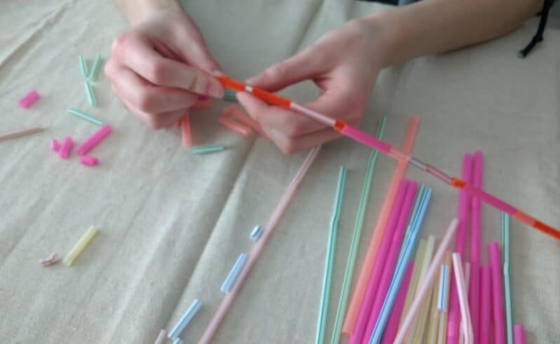 Threading straw pieces on to a pipe cleaner for DIY headband or necklace
