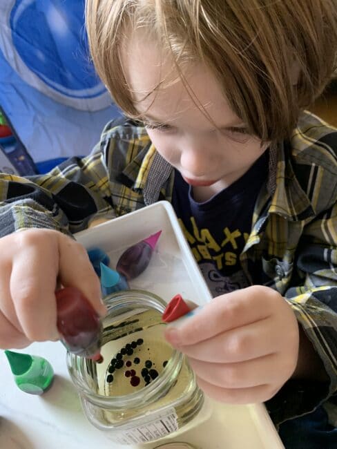 Fine motor practice squeezing food coloring drops into small jars of oil.