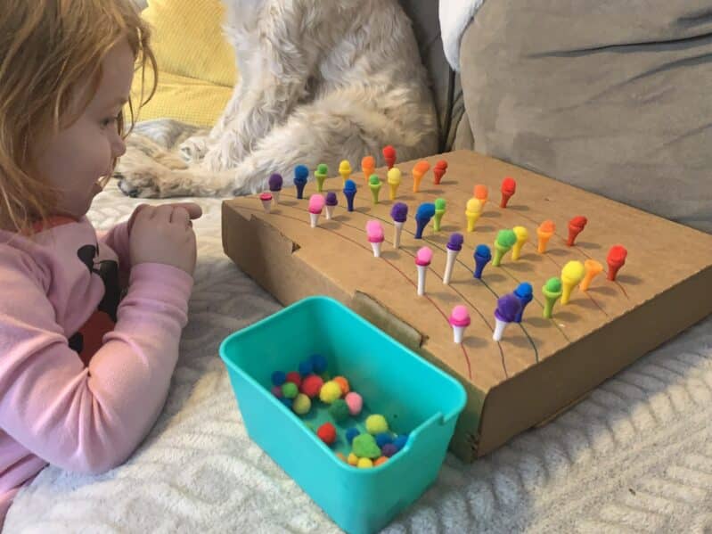 This simple color matching pom pom balancing activity is perfect for toddlers and preschoolers to challenge themselves and improve fine motor skills!