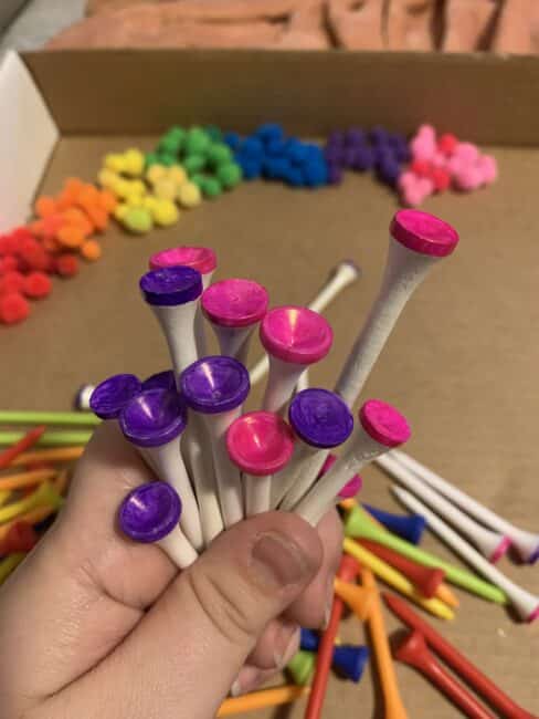 Color the tips of golf tees with permanent markers to make a rainbow