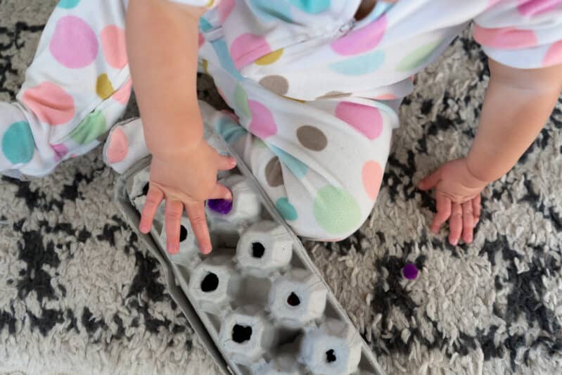 Work on fine motor skills with this easy to make fine motor push activity for toddlers using an egg carton and pom poms. Bonus, you can take it with you when you need to keep your toddler still and quiet!