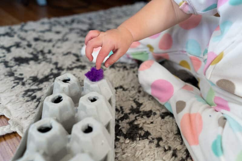 Make a simple fine motor pom pom push activity with an egg carton to take on the road or use at home to entertain your busy toddlers!