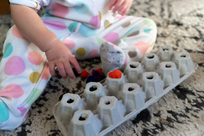 Make a simple fine motor pom pom push activity with an egg carton to take on the road or use at home to entertain your busy toddlers!