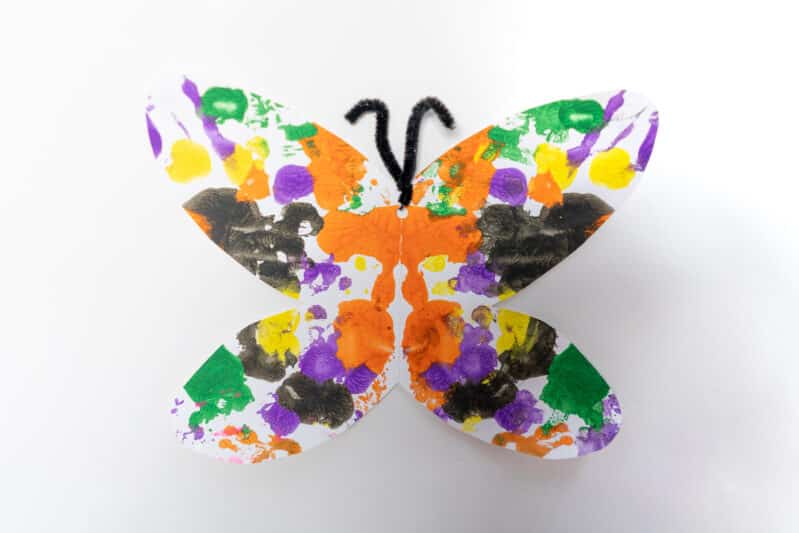 Make an adorable and beautiful butterfly using symmetrical blot painting technique with preschoolers at home on card stock and add a little pipe cleaner antenna for fun!