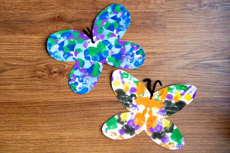 Preschoolers will love to make a super simple and pretty symmetrical butterfly painting by smooshing paint blobs inside a folded paper!