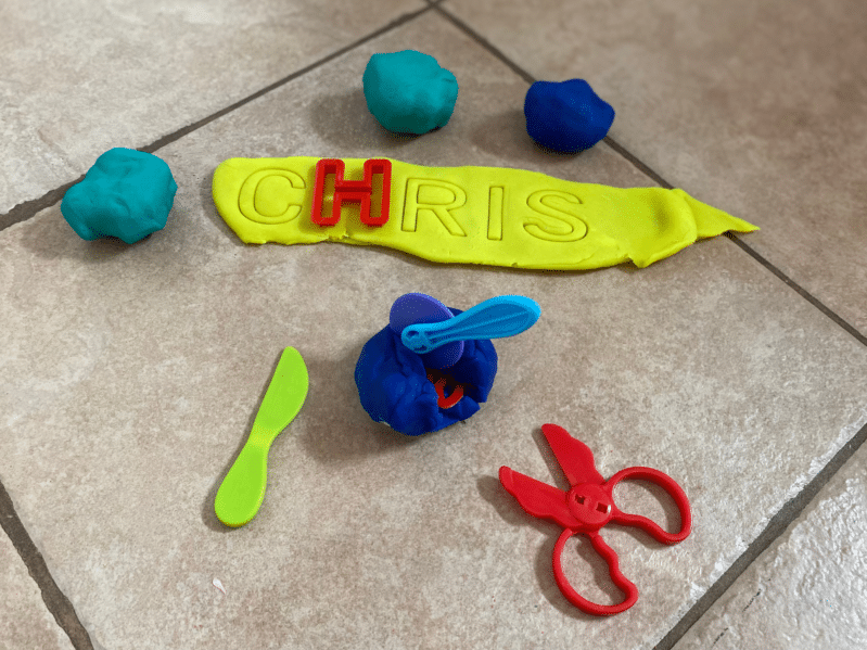 Preschoolers unwrap hidden treasures out of play dough! Simple fine motor fun. Add letter matching to it for a learning twist or try spelling their names.