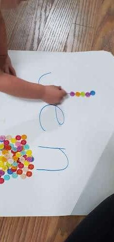 Trace letters of their name with buttons or other small objects