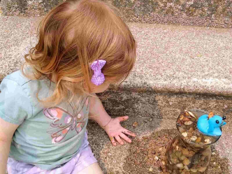 This super simple science experiment teaching water displacement while your toddlers use rocks to raise the water level to save their rubber ducky! Great busy play idea for toddlers in the backyard.