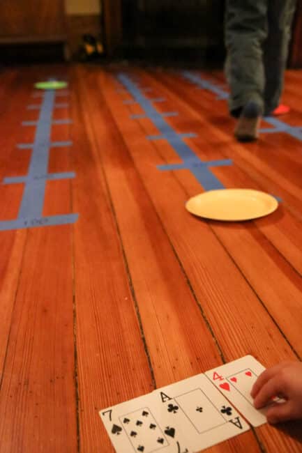 Teach number place values with this super simple gross motor number lines activity using painters tape, paper plates, and a deck of cards!