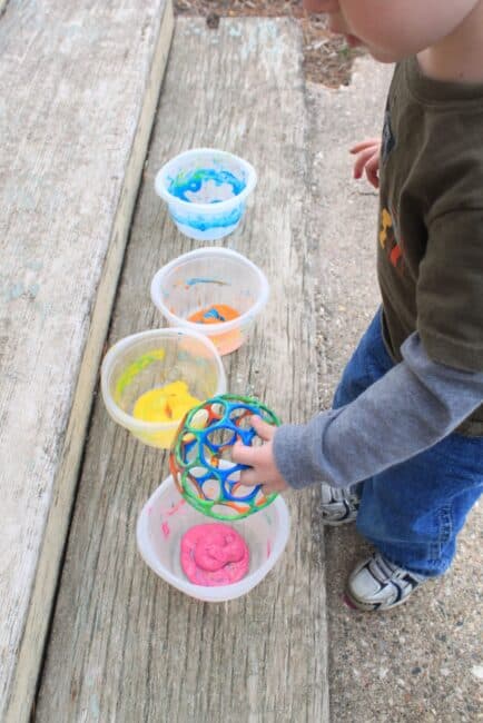 Set out different containers of paint to dip the eggs and balls into