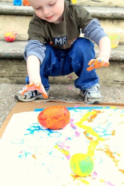 Rolling eggs down the paper to paint with movement.