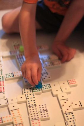 Child's hands matching dominoes laid out on the floor for a counting activity