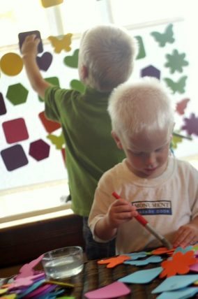 Child sticking foam shapes to a window to build a birthday cake