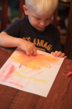 Child holding up a painting made by letting rain spread the colors