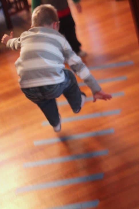 Burn off indoor energy with a simple tape jumping game to work on preschool gross motor skills!