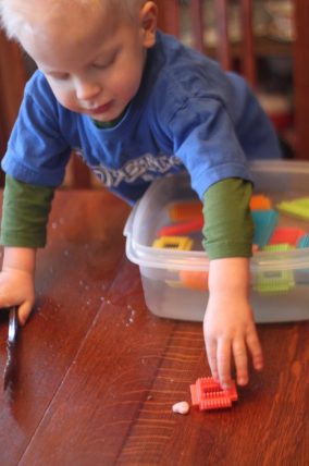 Child matching letters on candy hearts in a bin