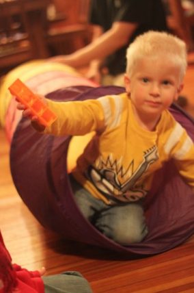 Child crawling out of a play tunnel during a color sorting game