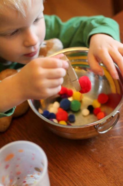 Build preschool fine motor skills by transferring pom poms with clothespins